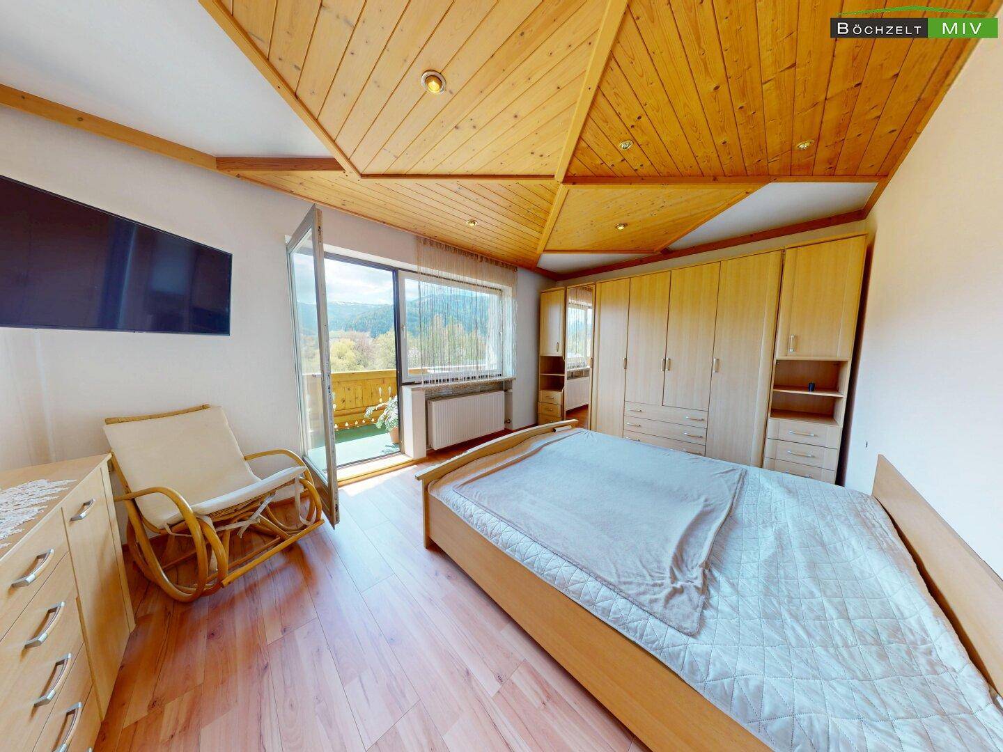Schlafzimmer mit Holzboden, Einbauschränken und Zugang zu einem Balkon mit Bergblick.