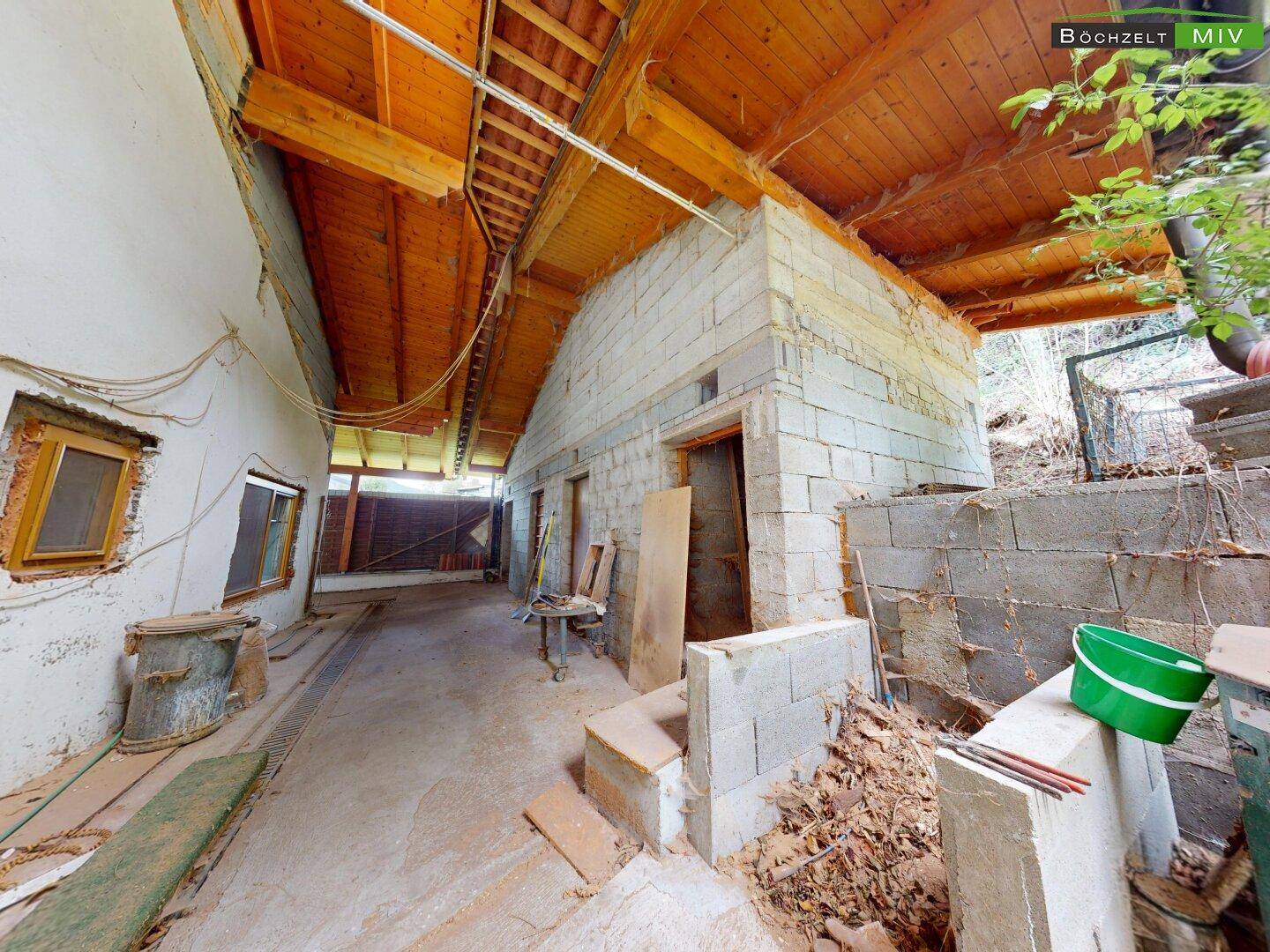Großer Garagenbereich mit Betonboden und Holzdecke, genutzt als Lager- und Arbeitsfläche.