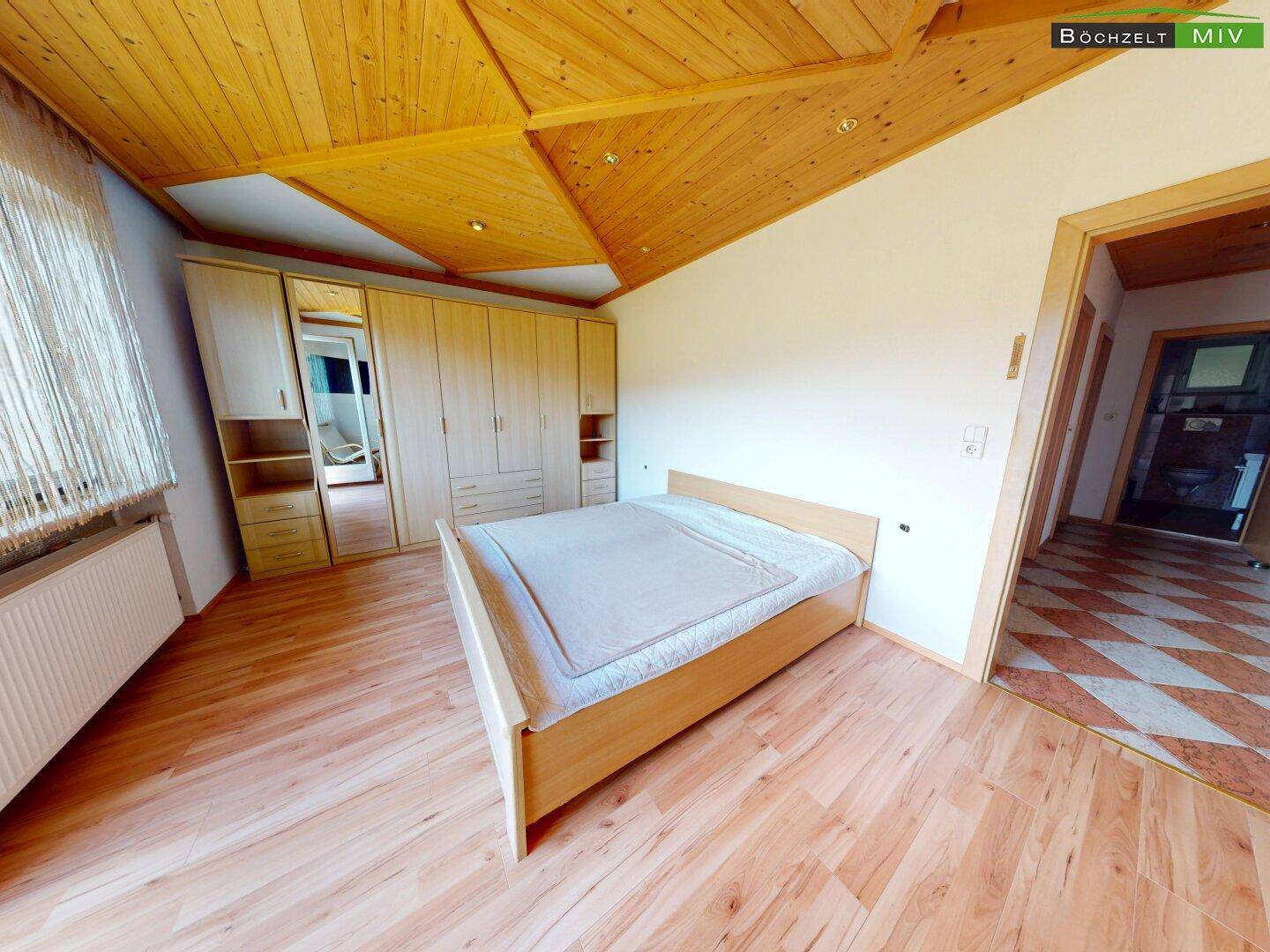 Schlafzimmer mit Holzboden, großem Kleiderschrank und Holzdecke im traditionellen Stil.