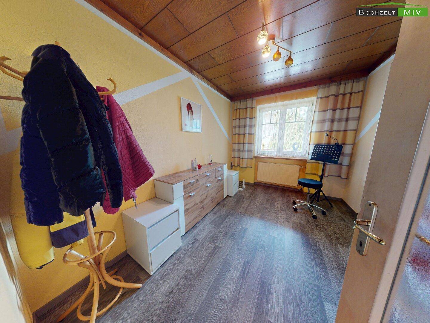 Helles Zimmer mit Holzdecke, Laminatboden und gelb gestrichenen Wänden, als Schlafzimmer oder Büro nutzbar.