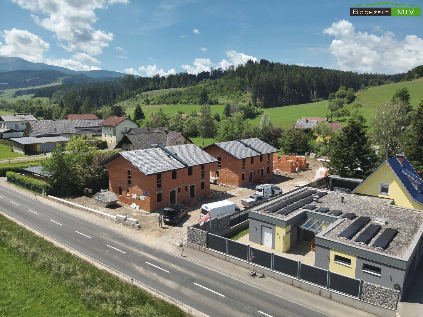 Panoramablick auf eine Wohnsiedlung im Grünen mit im Bau befindlichen Häusern und Solaranlagen.