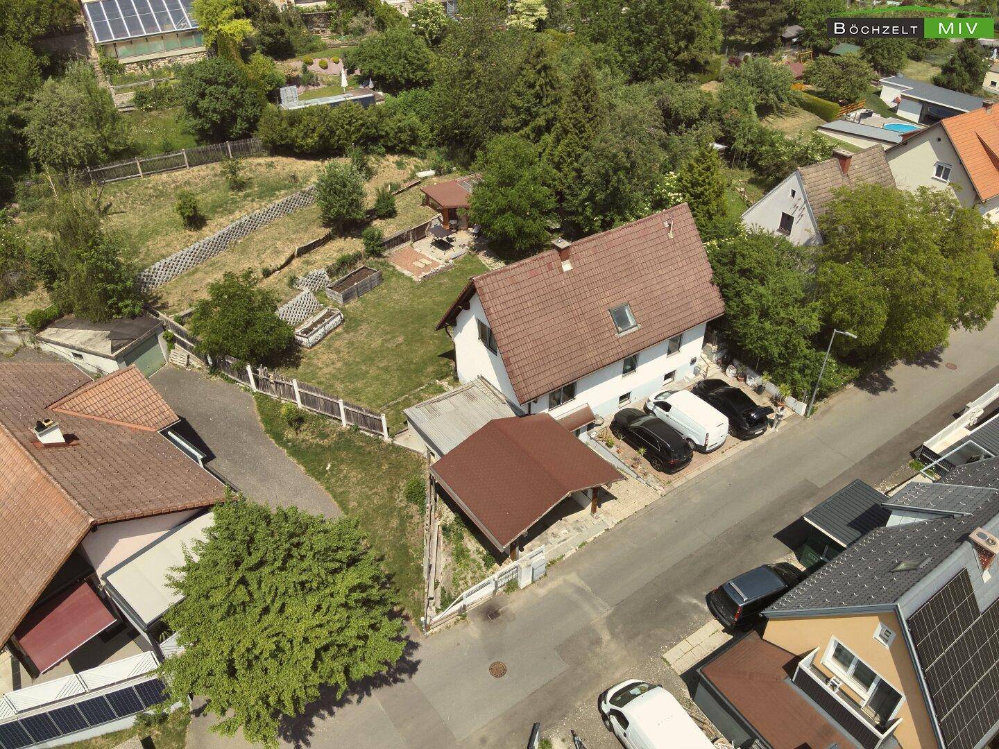 Drohnenaufnahme eines Einfamilienhauses mit großem Garten und Carport in ländlicher Umgebung.