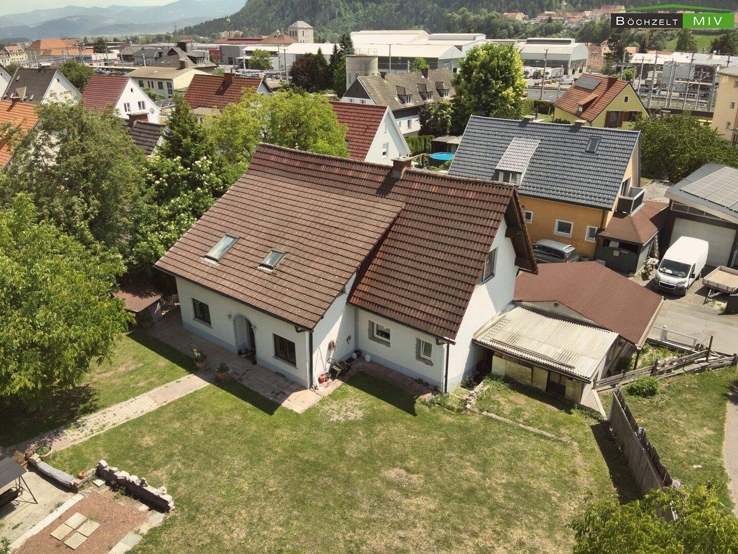Luftaufnahme des Einfamilienhauses mit gepflegtem Rasen und angrenzendem Carportbereich.