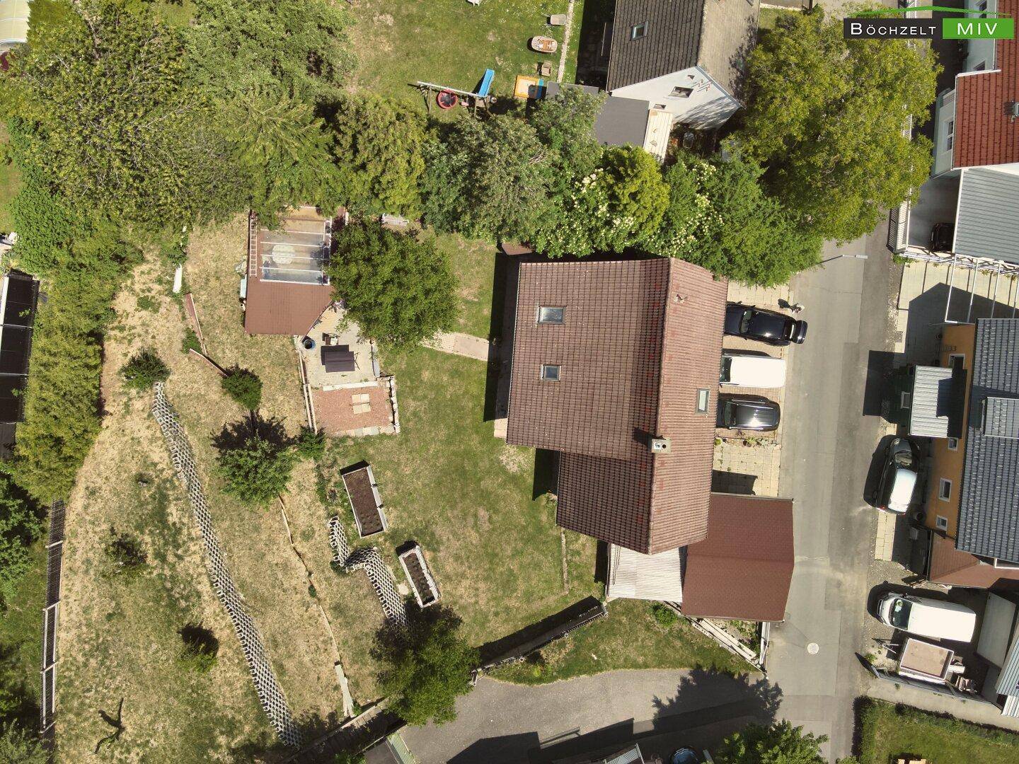 Senkrechte Draufsicht auf das Wohnhaus mit Garten, Carport und umliegenden Wegen.