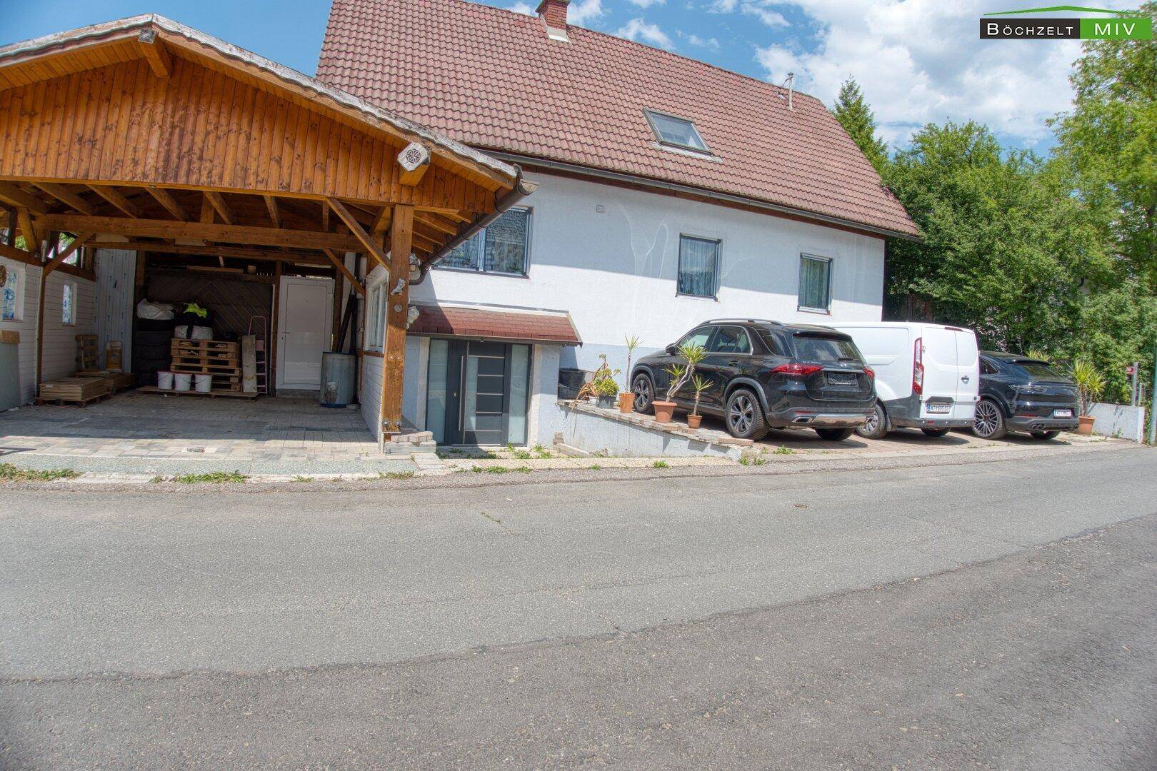 Gesamtansicht des Hauses mit Carport und Stellplätzen für Fahrzeuge von der Straße aus.
