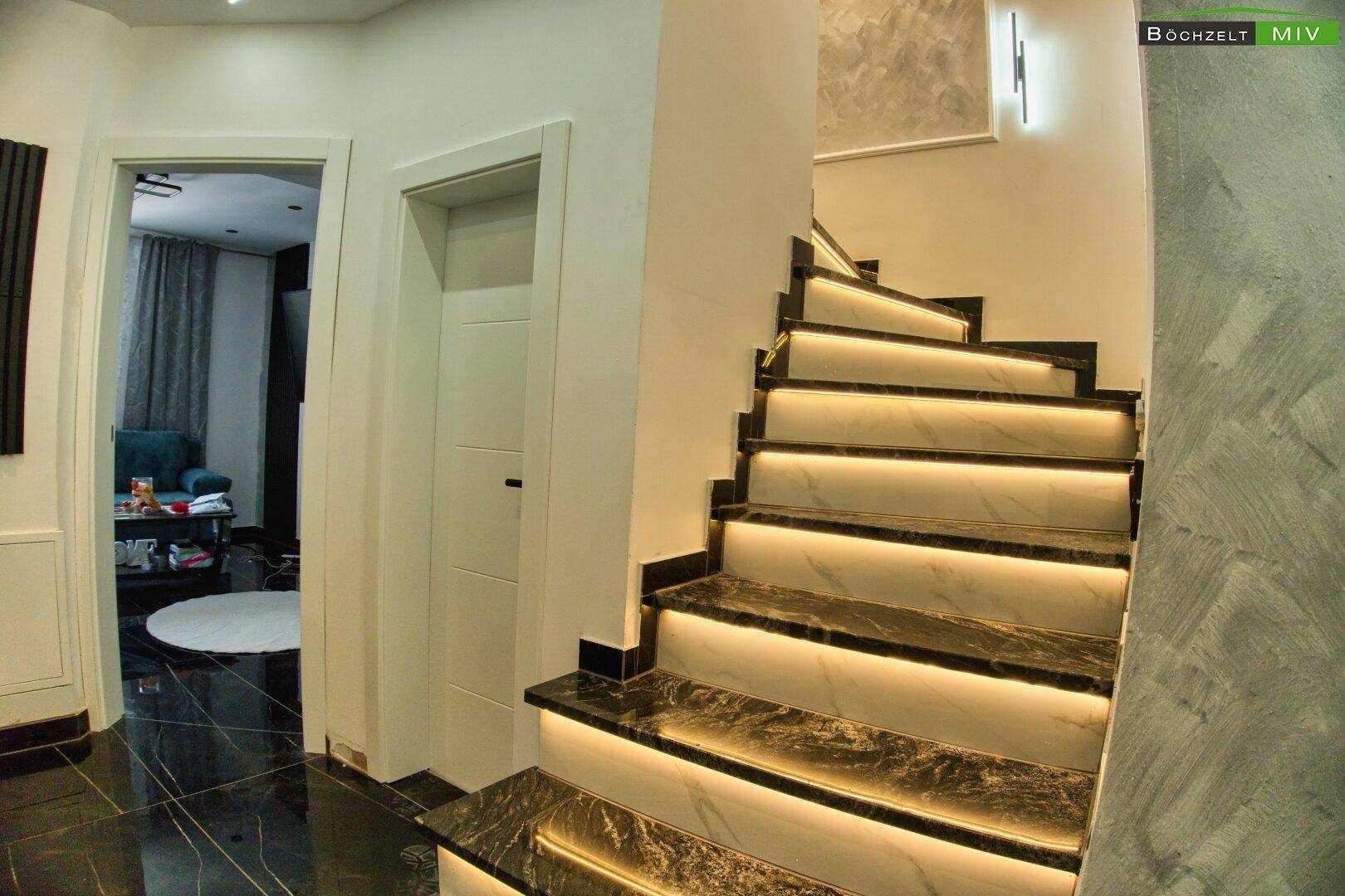 Elegante Treppe mit integrierter Beleuchtung und dunklen Marmorstufen im Flur.