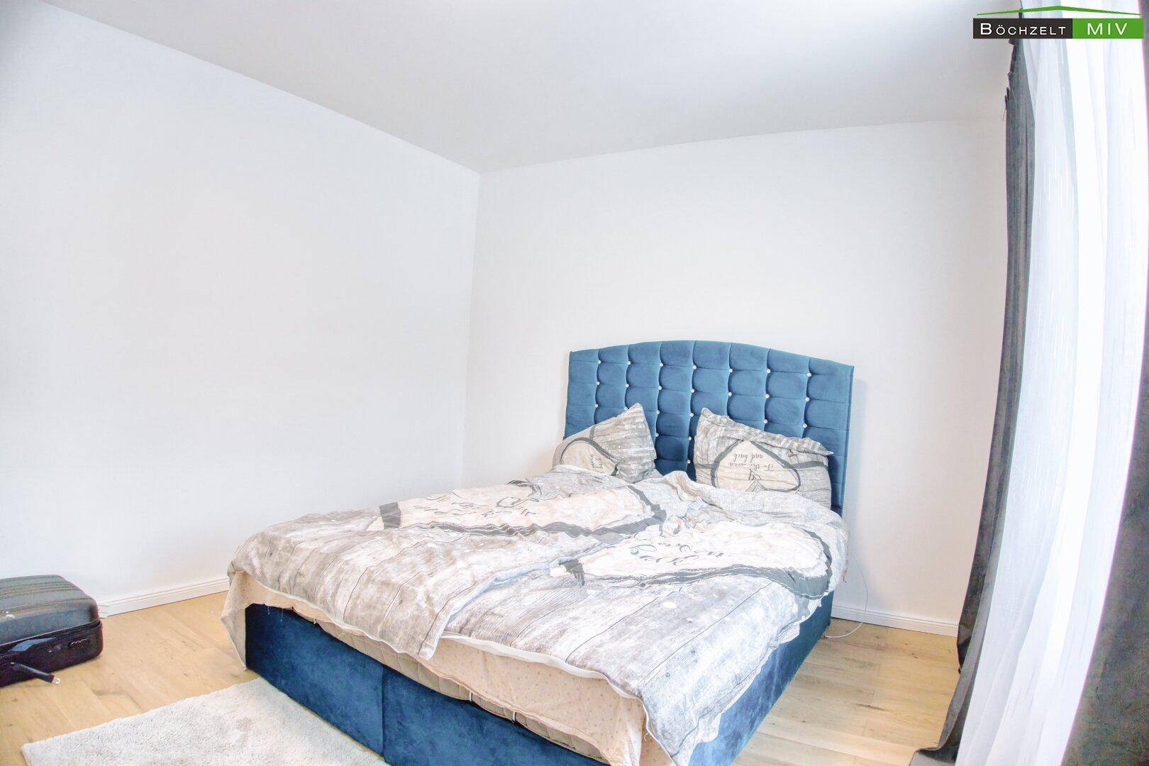 Helles Schlafzimmer mit Holzboden und großem Fenster.