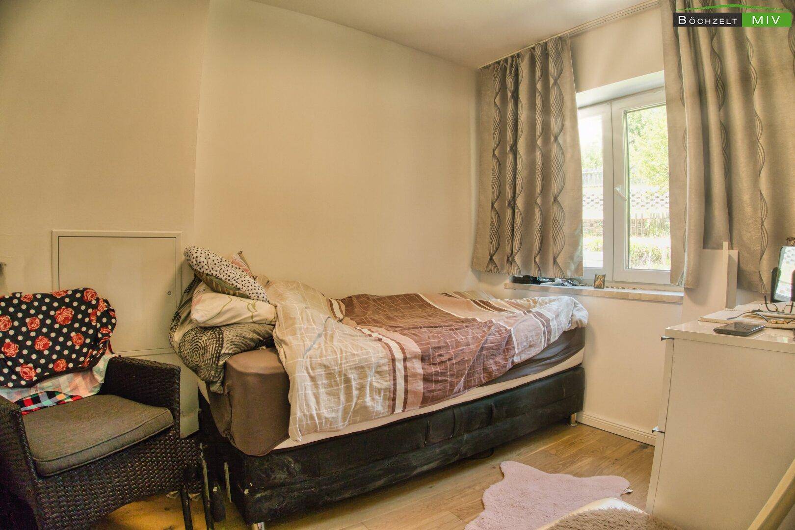 Schlafzimmer mit Einzelbett, Fenster und Holzboden.