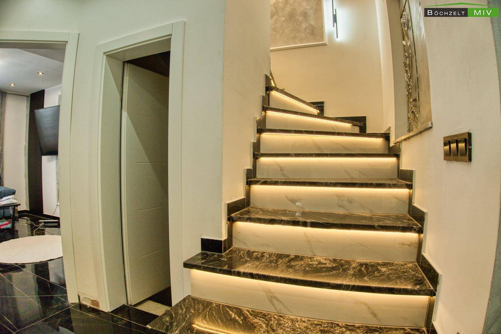 Beleuchtete Marmortreppe im modernen Stil mit dunklen Stufen.