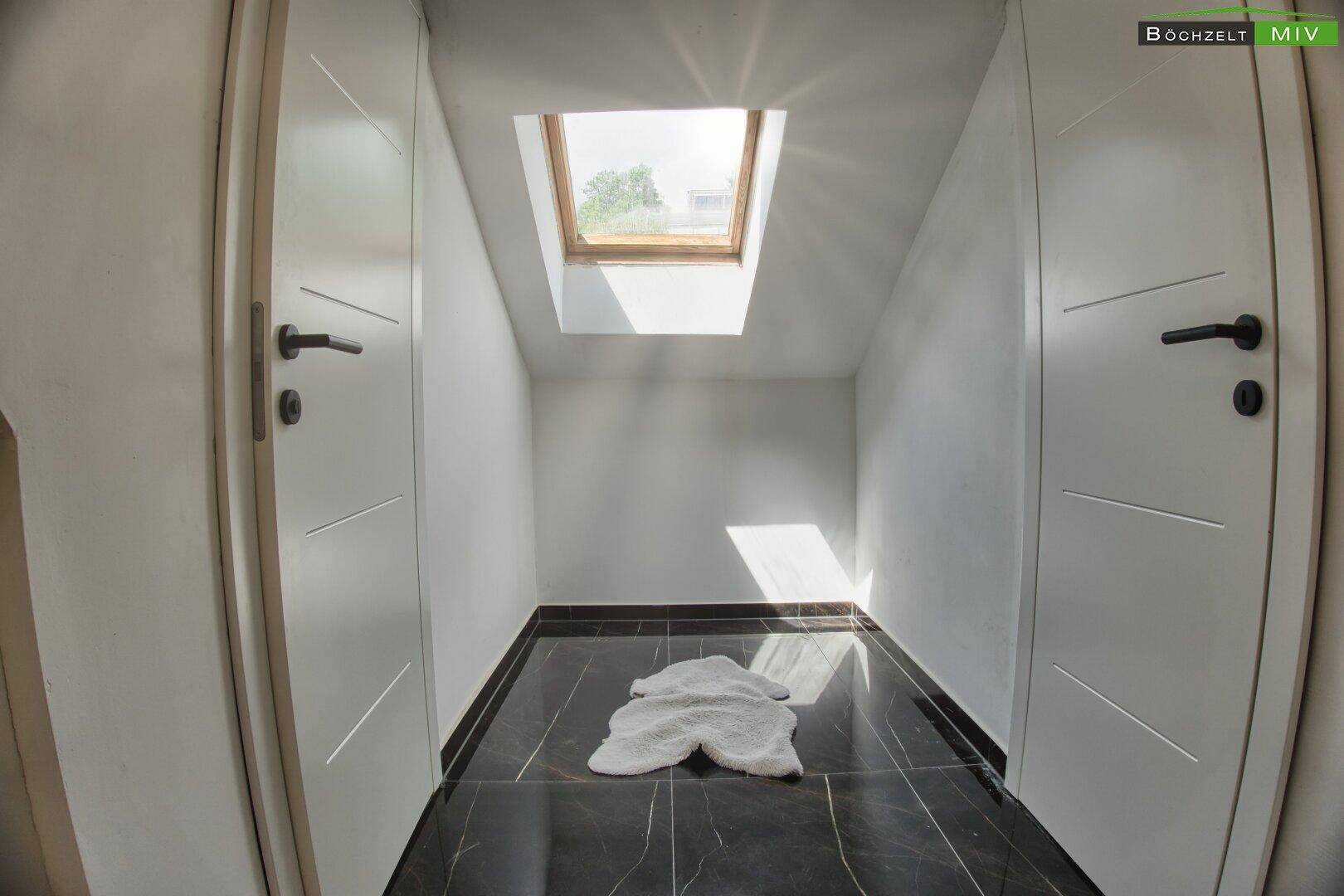 Kleiner Raum im Dachgeschoss mit Dachfenster und dunklem Fliesenboden.