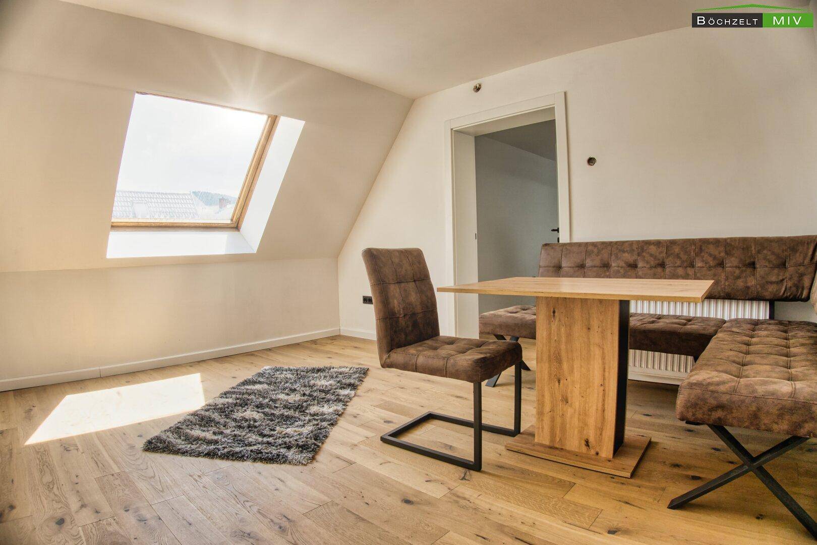 Heller Essbereich im Dachgeschoss mit Holzboden, Dachfenster und moderner Sitzgruppe.