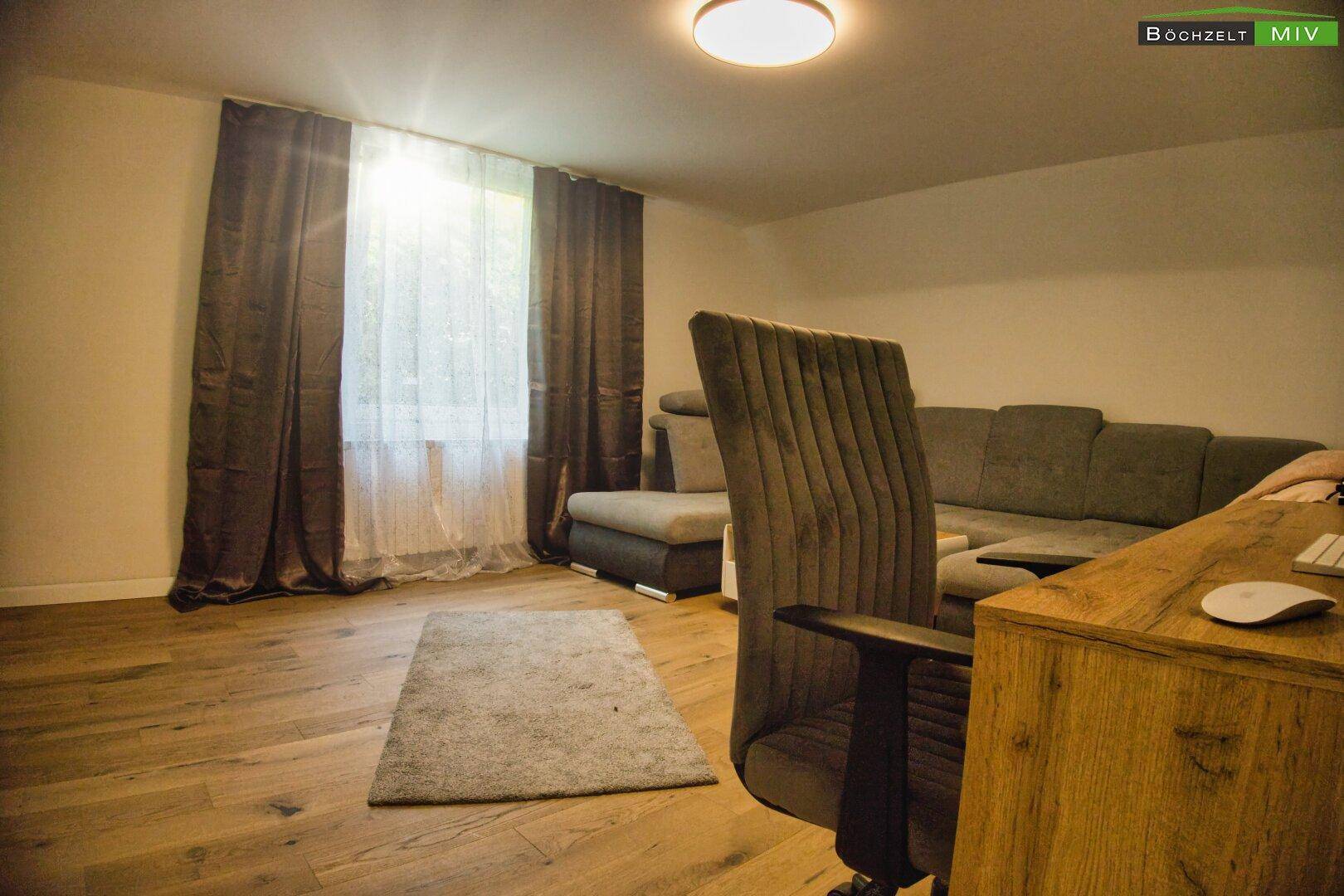Wohnzimmer mit großem Fenster, Sofa und Schreibtisch, ideal für Entspannung und Arbeit.