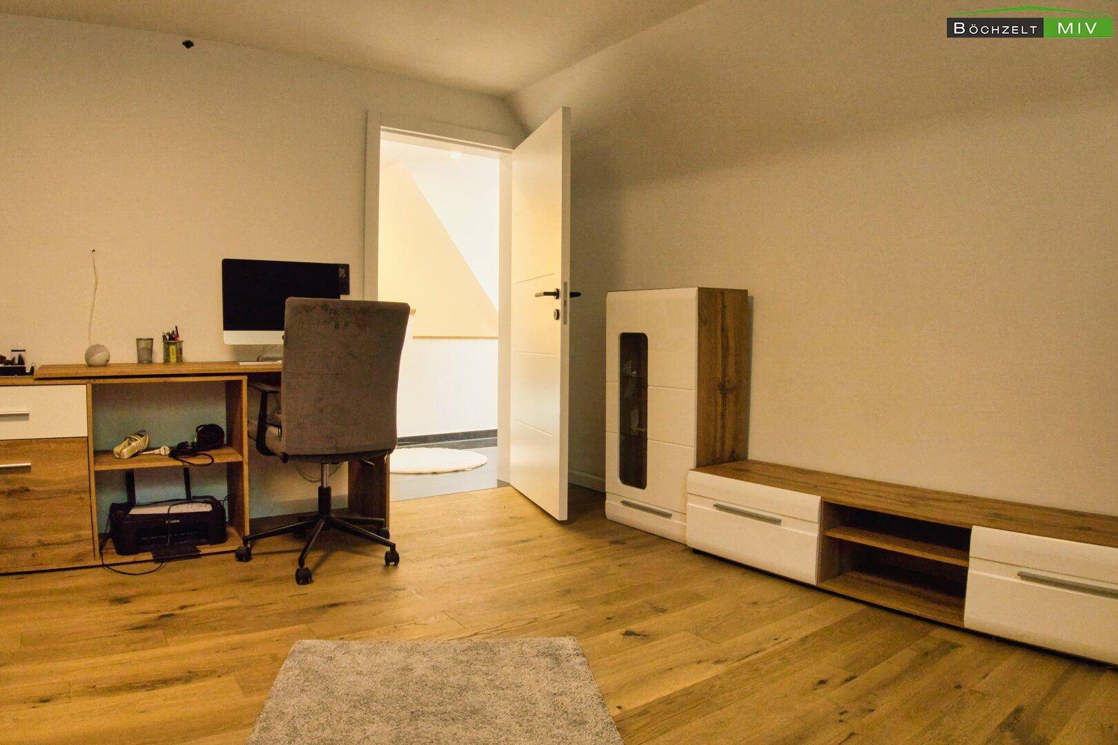 Wohnzimmer mit Sofa, Schreibtisch und modernen Möbeln, mit Zugang zum Flur.