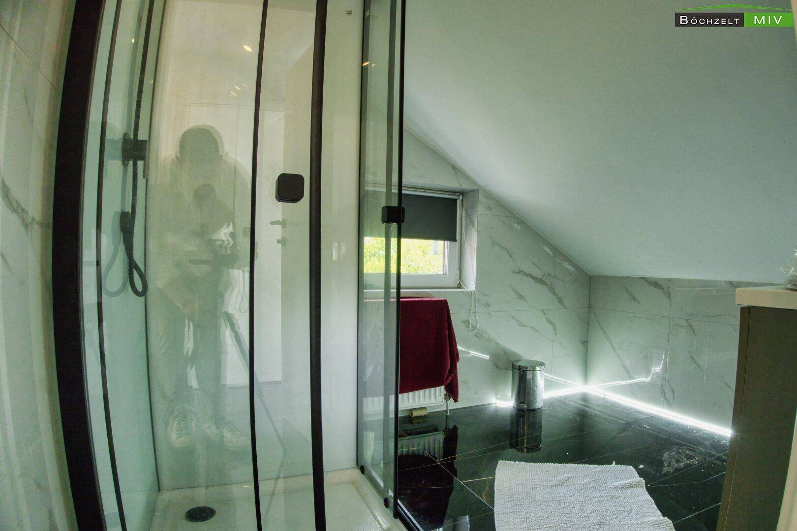 Modernes Badezimmer mit Duschkabine, Marmorfliesen und Dachschräge.