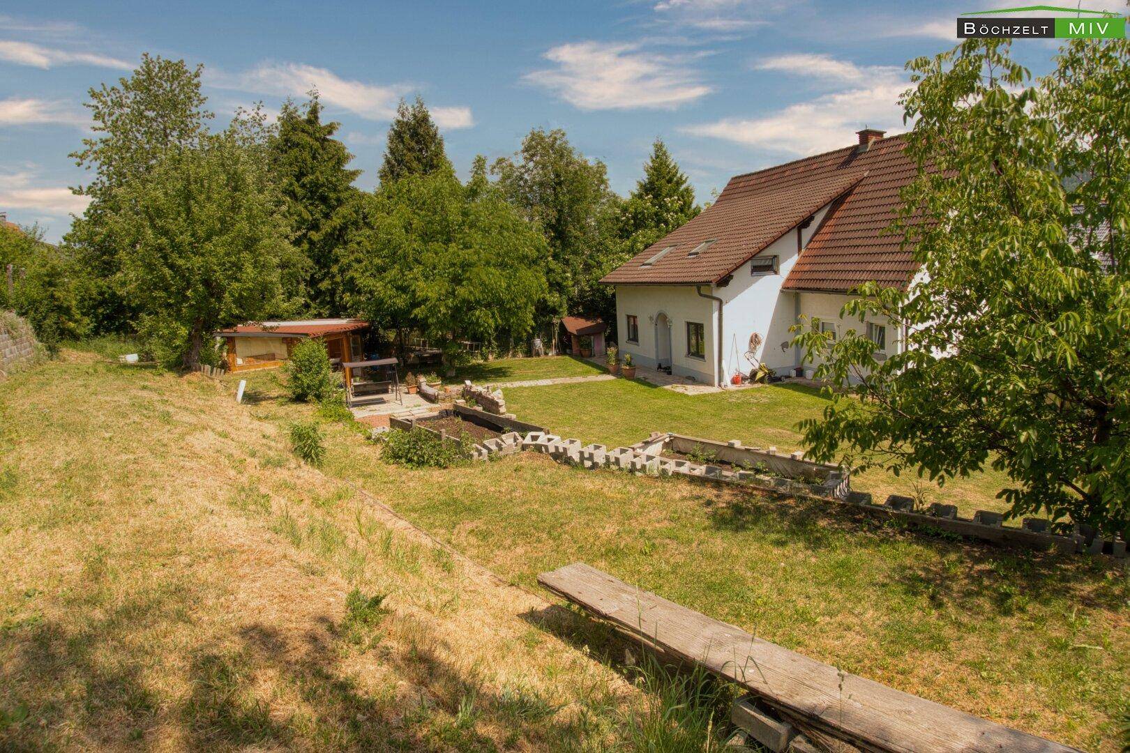 Großzügiger Gartenbereich mit Rasenfläche, Bäumen und einem charmanten Haus im Hintergrund.