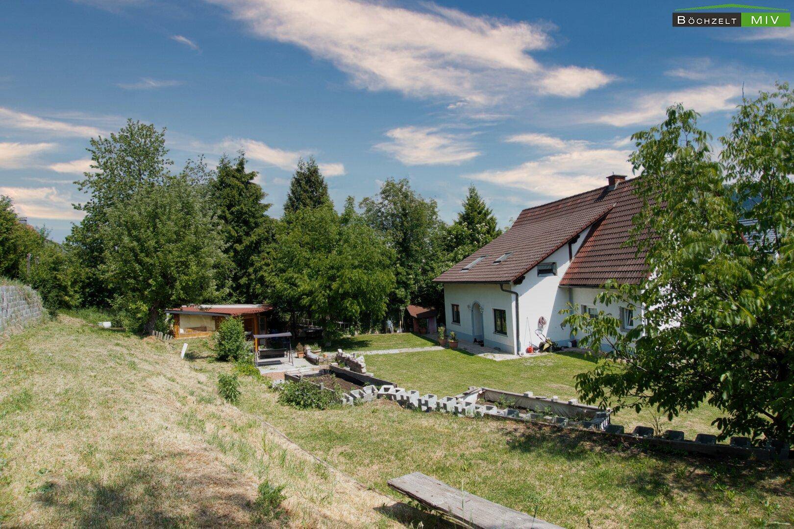 Gartenbereich mit Rasenfläche und Blick auf das Einfamilienhaus mit Satteldach.