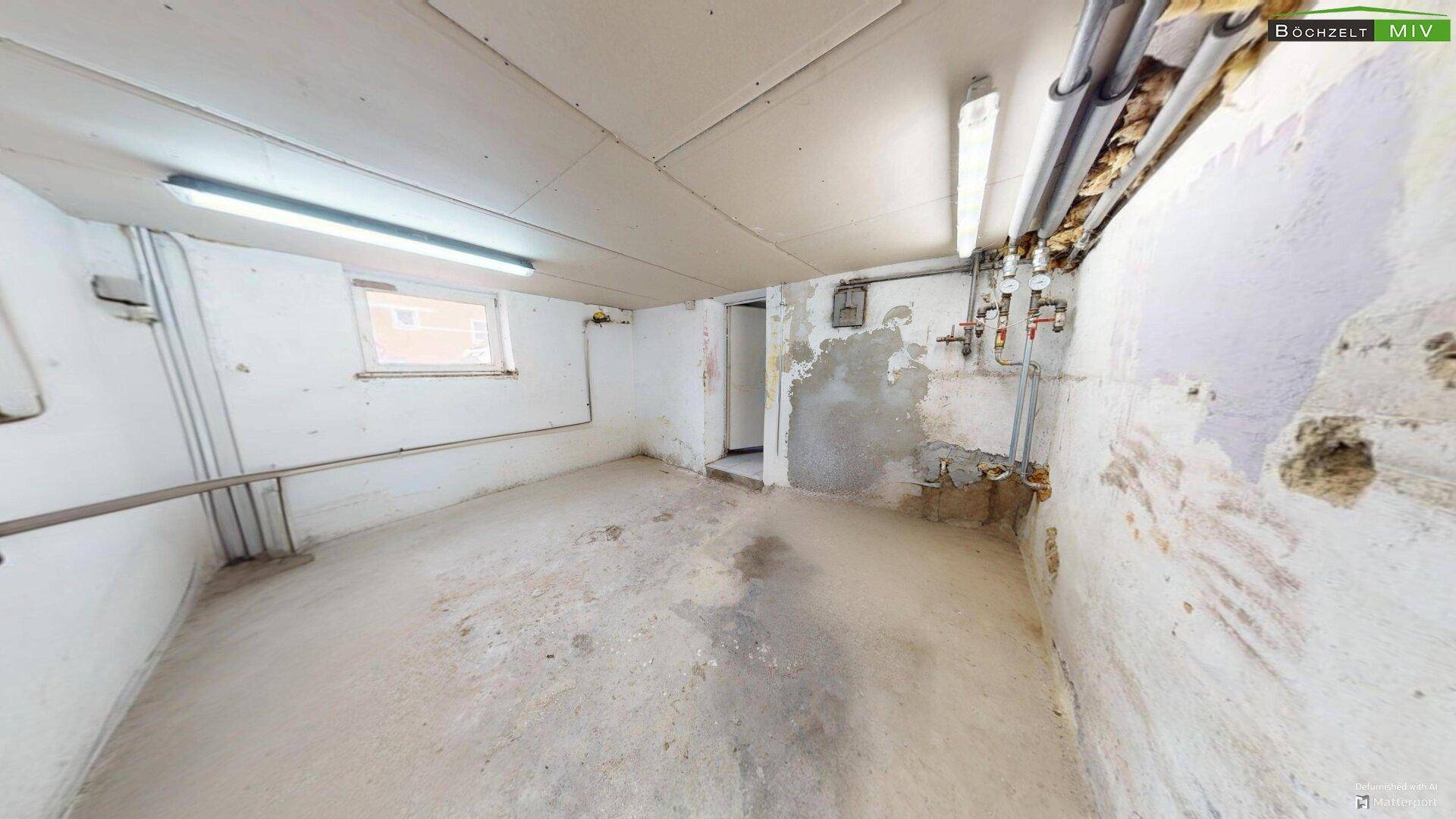 Unfertiger Kellerraum mit Betonboden, sichtbaren Rohren und Renovierungsbedarf.