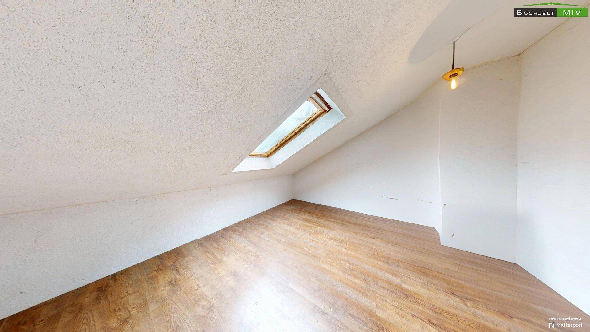 Helles Dachzimmer mit schräger Decke, Dachfenster und Laminatboden.