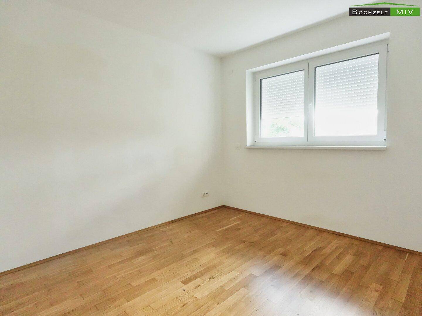 Helles Zimmer mit Parkettboden und Fenster mit Rollladen, ideal als Schlaf- oder Arbeitszimmer.