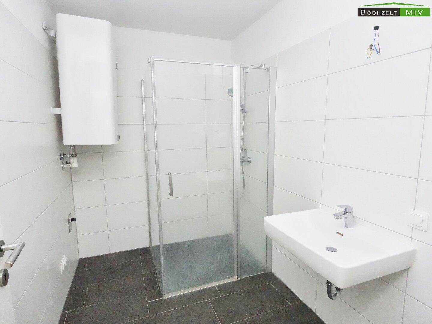 Modernes Badezimmer mit Dusche, Waschbecken und weißen Fliesen, sehr gepflegt.