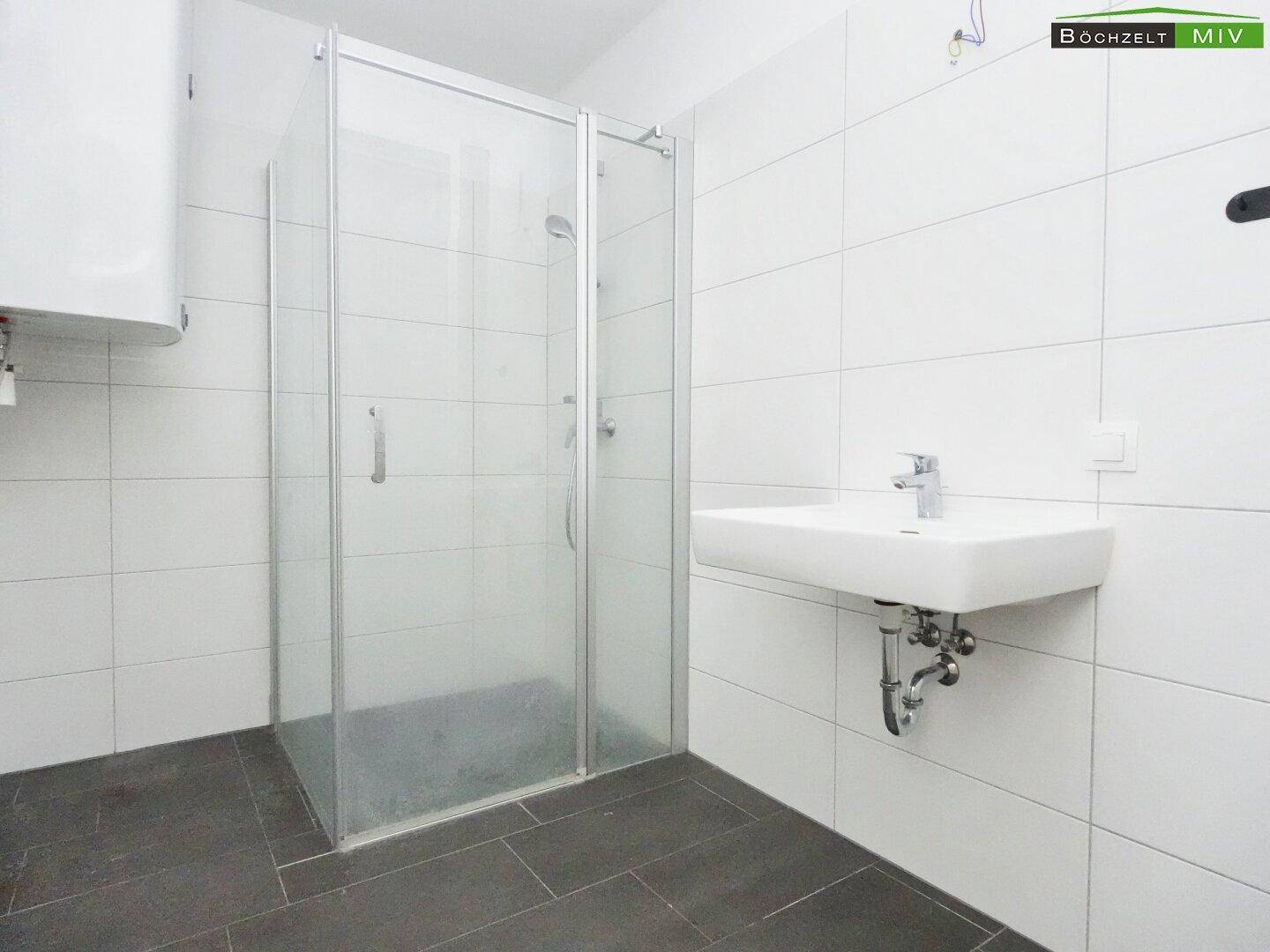 Modernes Badezimmer mit Dusche, Waschbecken und weißen Fliesen, sehr gepflegt.