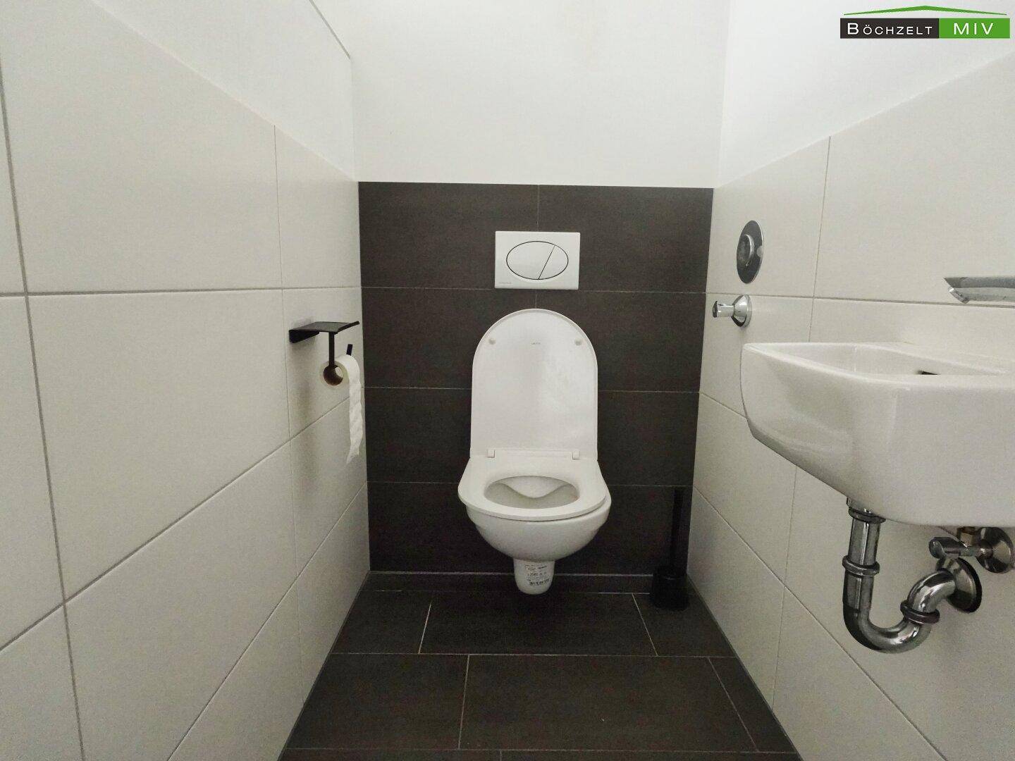 Modernes Gäste-WC mit wandhängender Toilette und Waschbecken, in neutralen Farben gehalten.