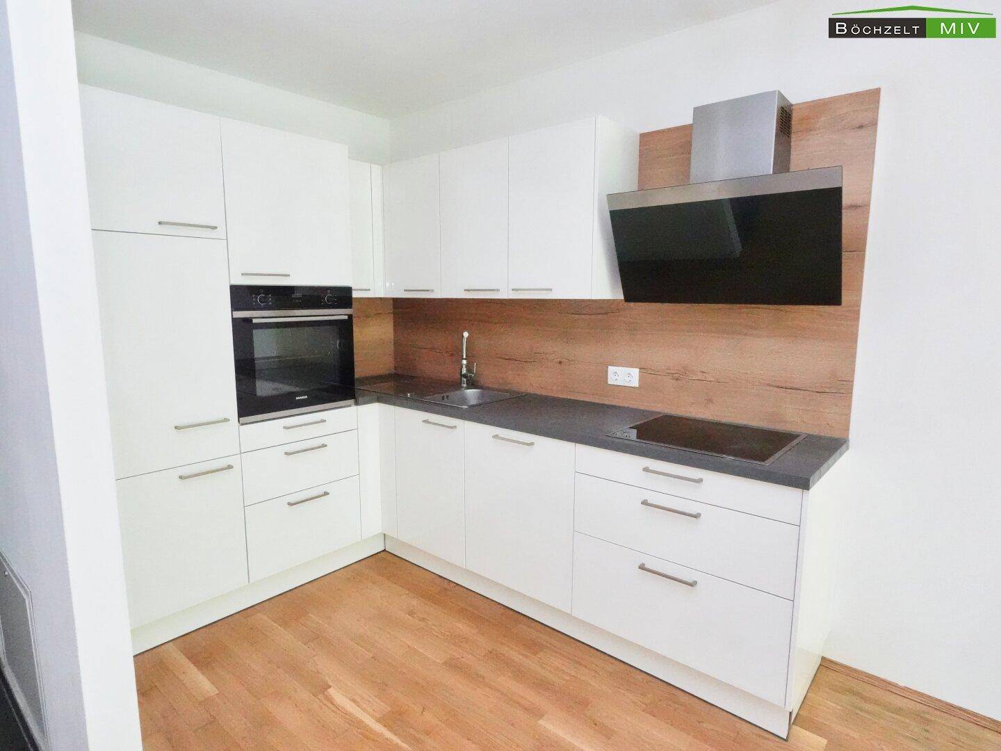 Moderne Einbauküche mit weißen Fronten, Induktionskochfeld und integriertem Backofen.