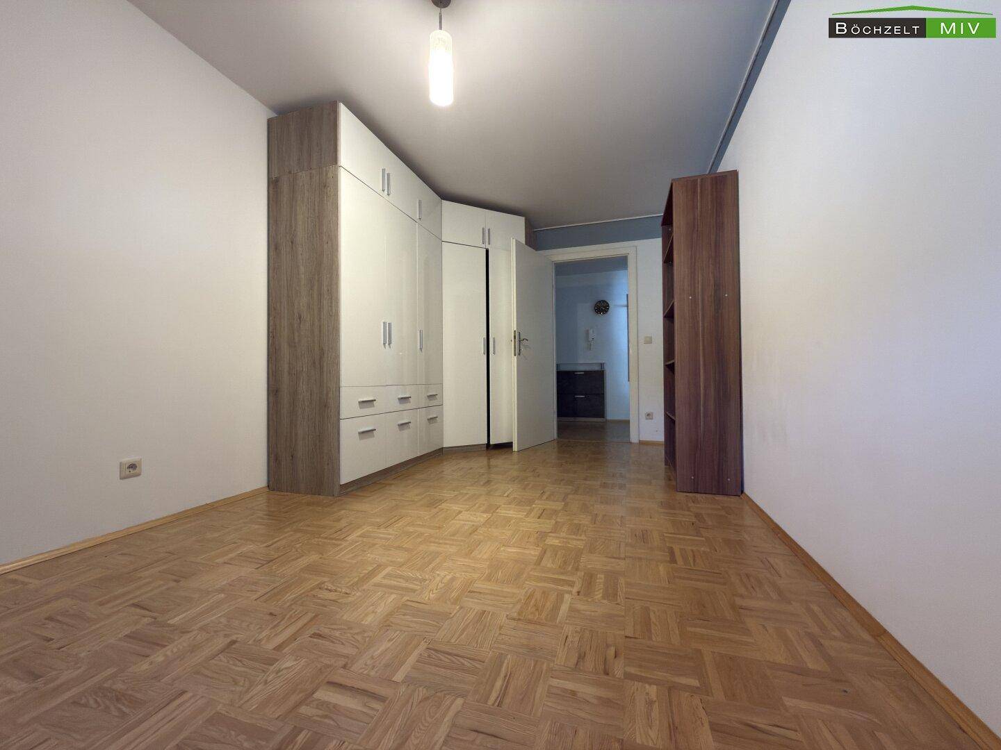 Geräumiges Zimmer mit Parkettboden und großem Einbauschrank.