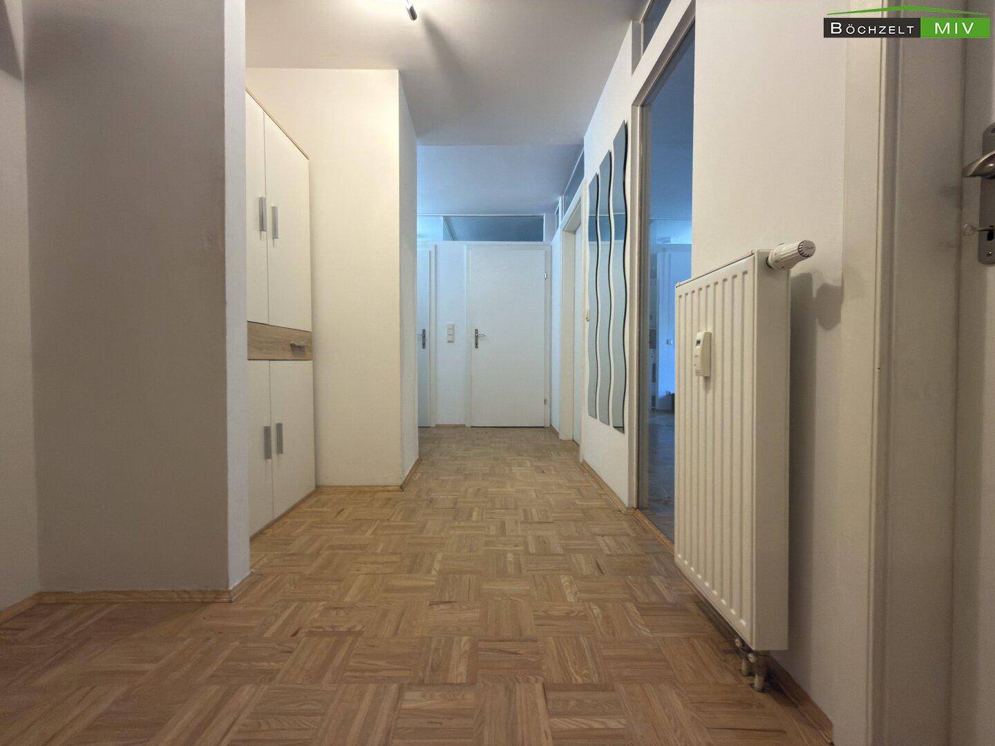 Heller Flur mit Parkettboden und Einbauschrank.