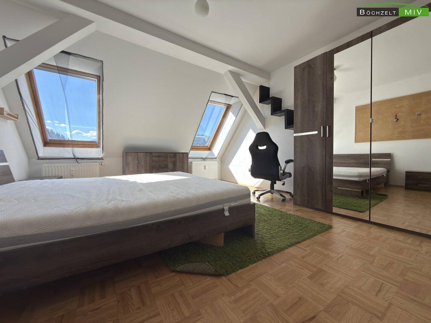 Helles Schlafzimmer im Dachgeschoss mit großem Spiegelkleiderschrank und Dachfenstern.