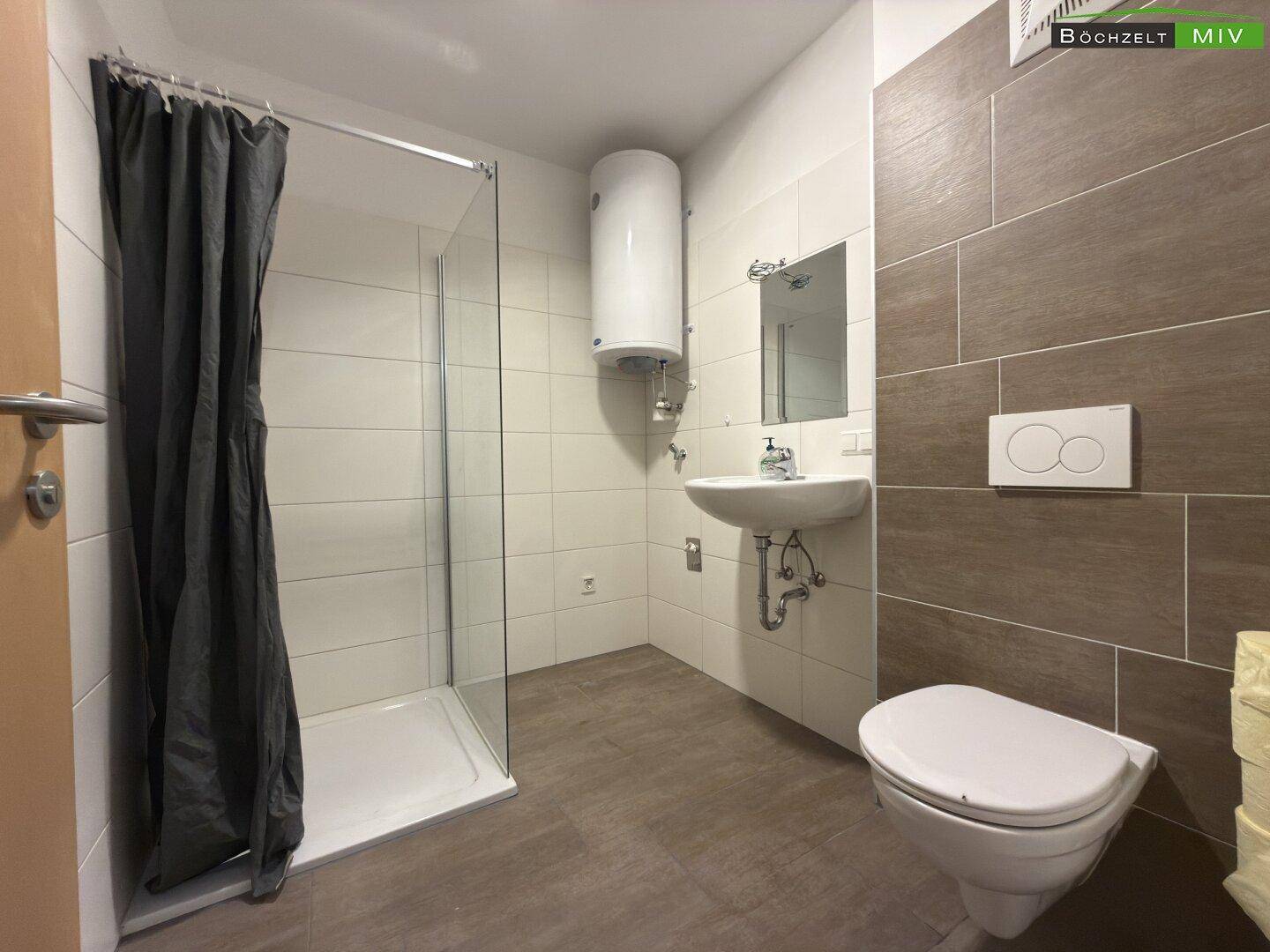 Modernes Badezimmer mit Duschkabine, wandhängendem WC, Waschbecken und weiß-braunen Fliesen.
