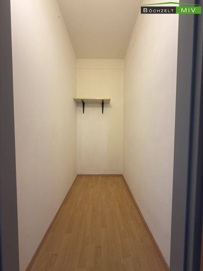 Schmaler Abstellraum mit Laminatboden und einer einfachen Ablagefläche an der Wand.
