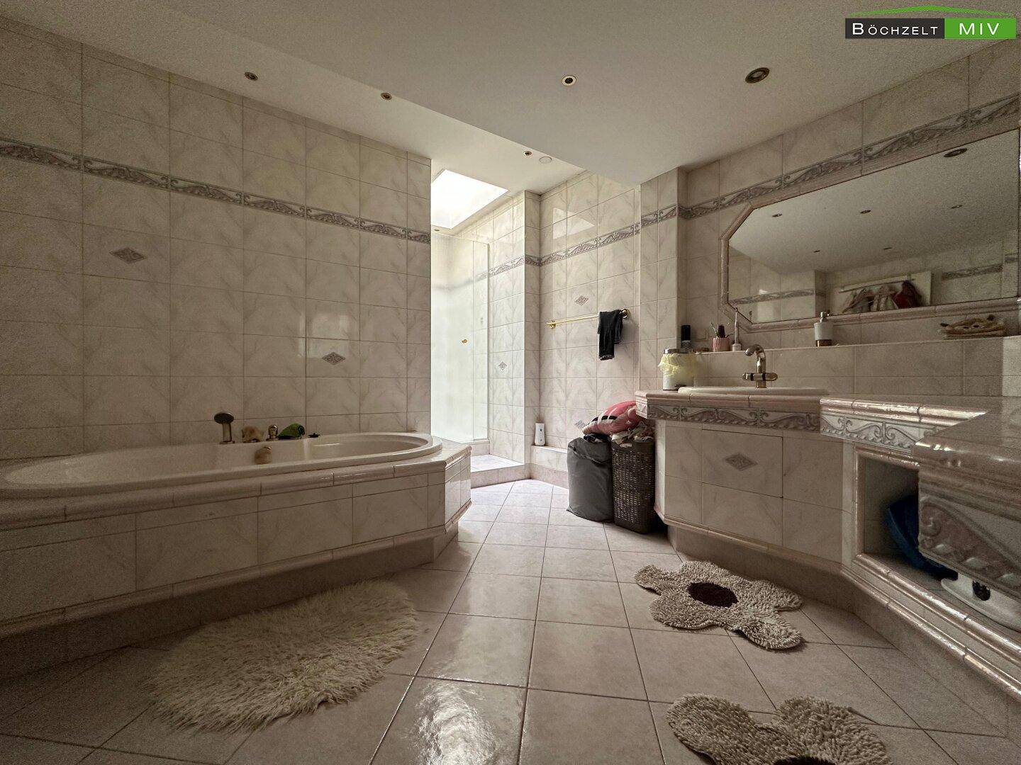 Geräumiges Badezimmer mit Fliesenboden, Badewanne und separater Dusche unter einem Oberlicht.