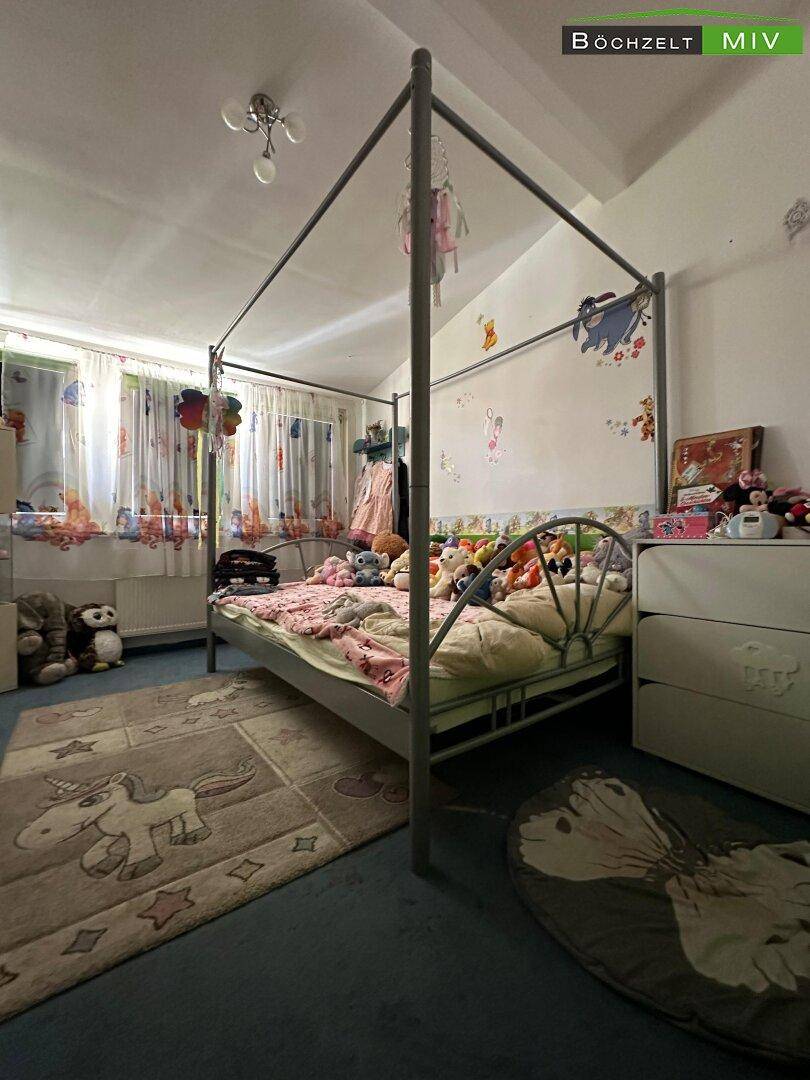 Kinderzimmer mit Himmelbett, Teppichboden und verspielter Wanddekoration.