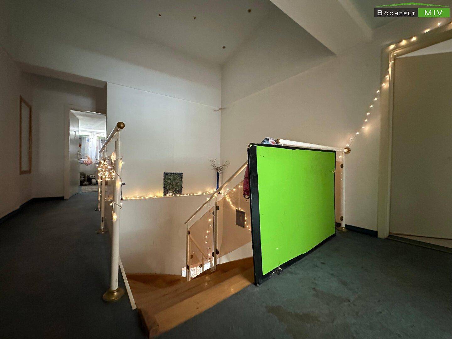 Oberer Flur mit Teppichboden und einer Treppe, die nach unten führt.