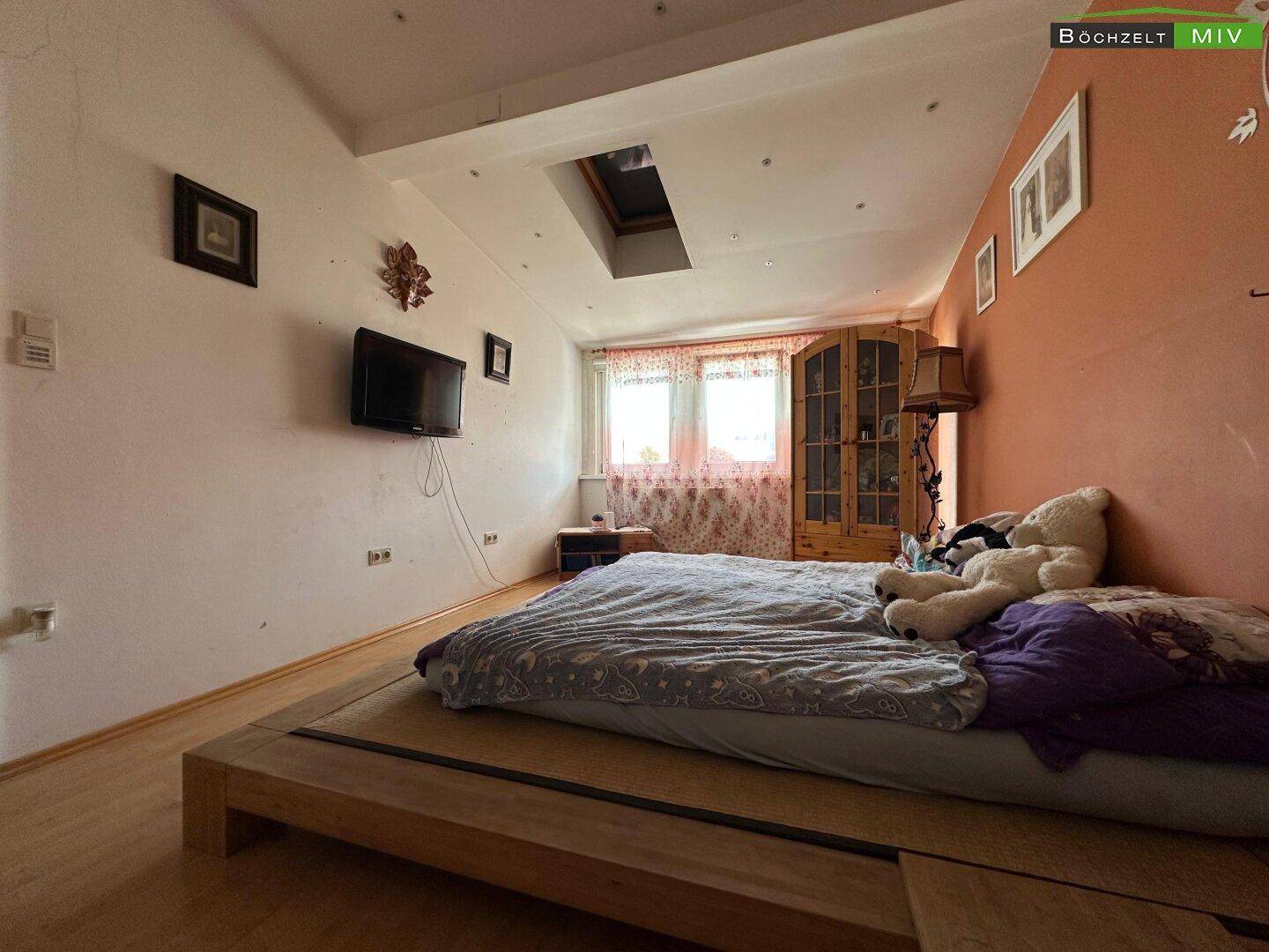 Schlafzimmer mit Holzboden, Dachfenster und einem Doppelbett.
