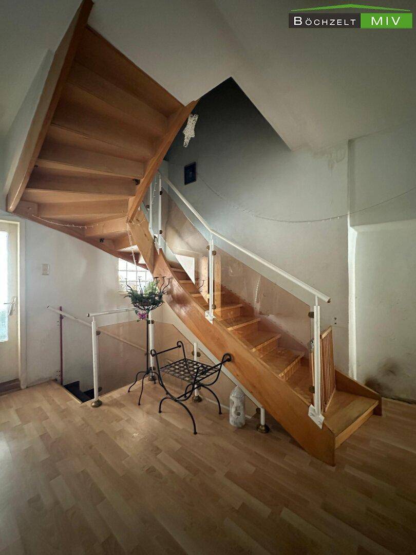 Holztreppe mit Glasgeländer, die die Stockwerke verbindet und helles Licht hereinlässt.