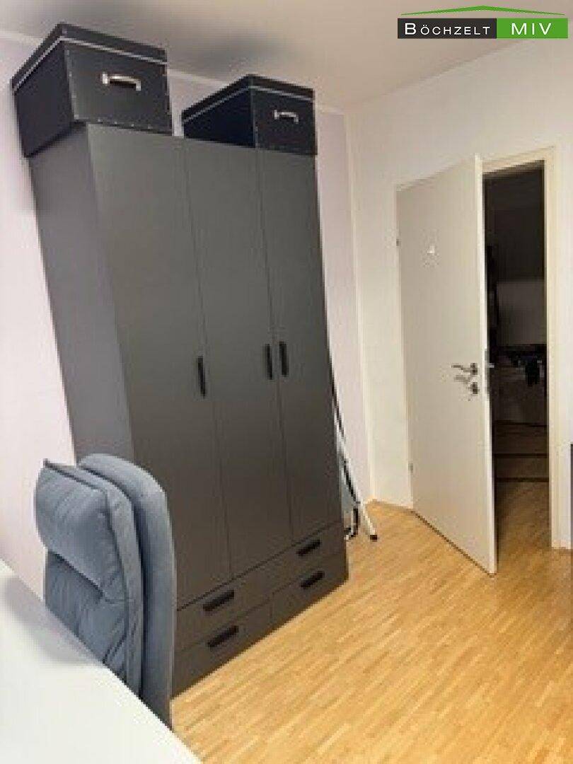 Zimmer mit großem, dunklem Kleiderschrank und Holzboden, ideal als Schlaf- oder Gästezimmer.