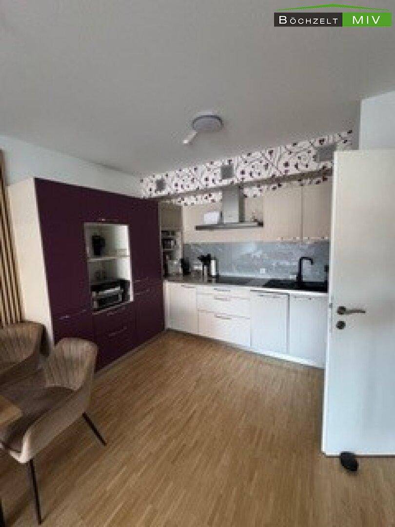 Moderne Küche mit lila und weißen Schränken, integrierter Spüle und Holzboden.