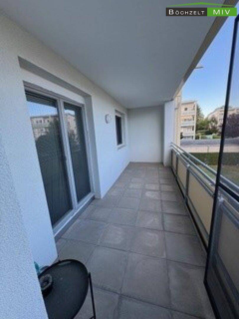 Langer Balkon mit Fliesenboden und Blick auf die Umgebung, ideal zum Entspannen.