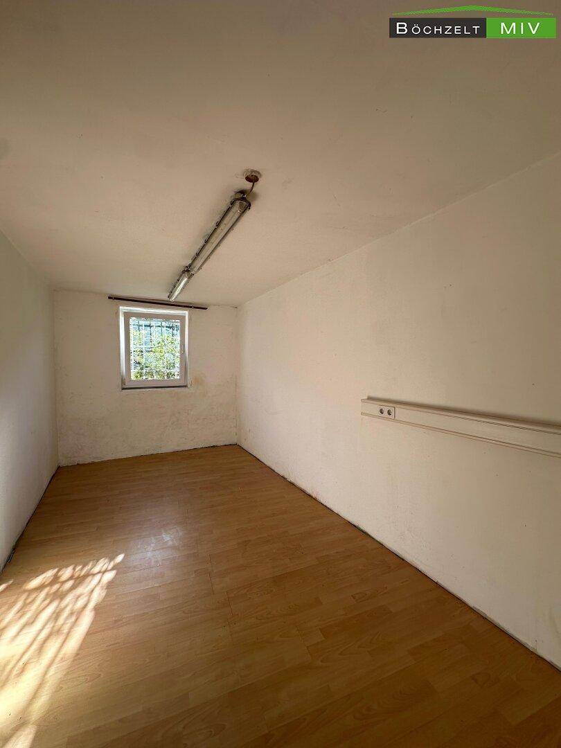 Kleiner Lagerraum oder Büro mit Laminatboden und einem Fenster, das für natürliche Belichtung sorgt.