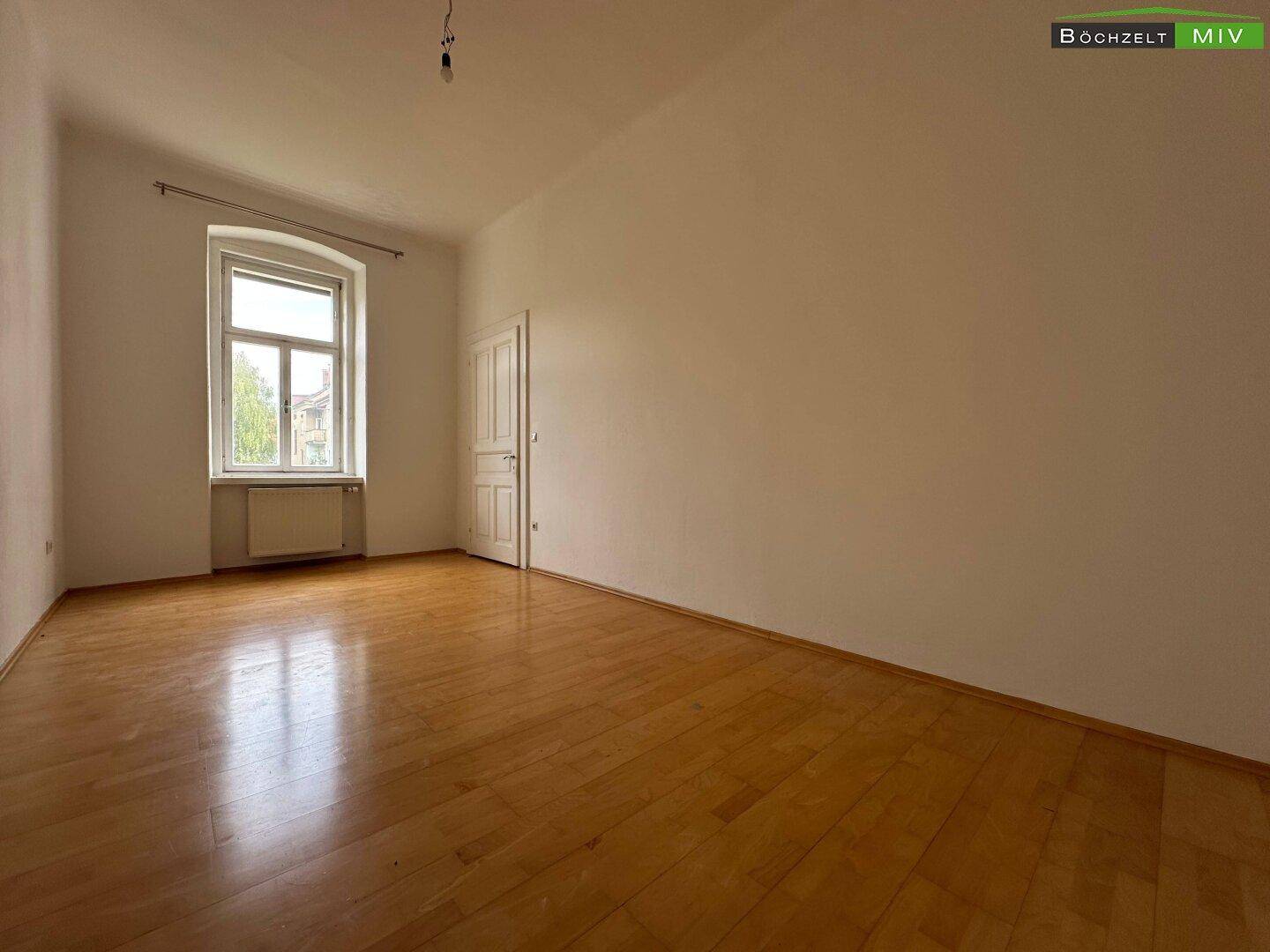 Leeres Zimmer mit Parkettboden und einem Fenster, bereit zur individuellen Gestaltung und Nutzung.
