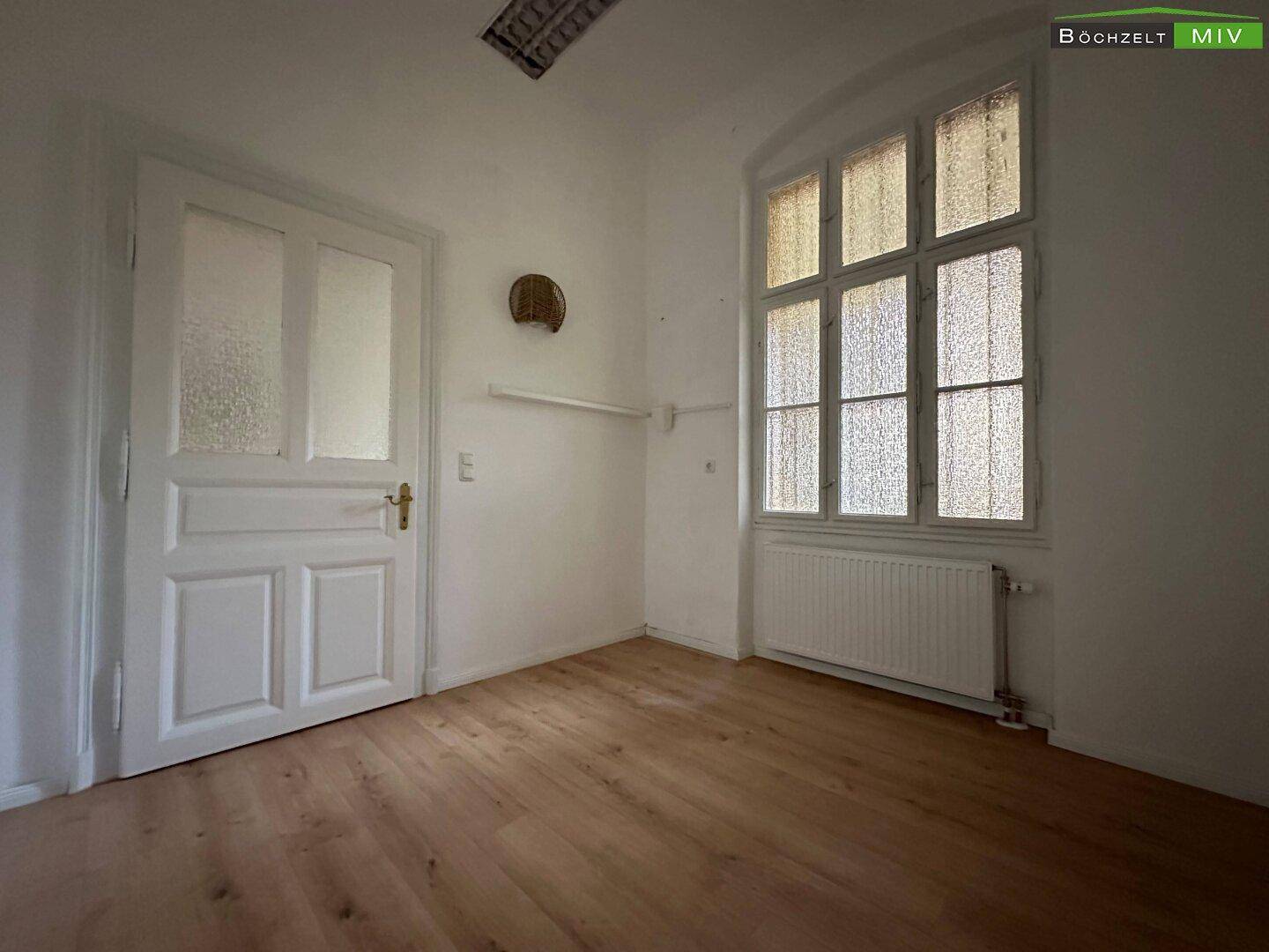 Kleiner Raum mit Laminatboden und einem großen Fenster mit Sprossen.