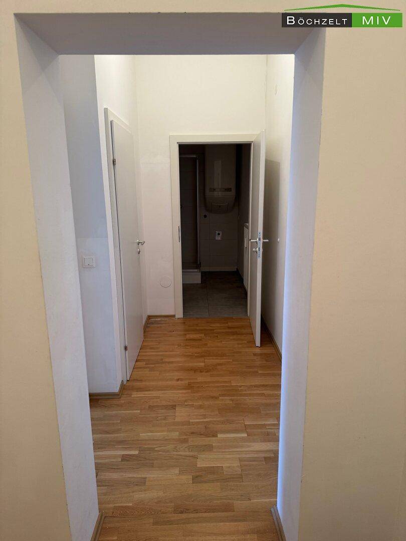Langer Flur mit Holzboden, der den Zugang zu verschiedenen Zimmern und einem Bad ermöglicht.