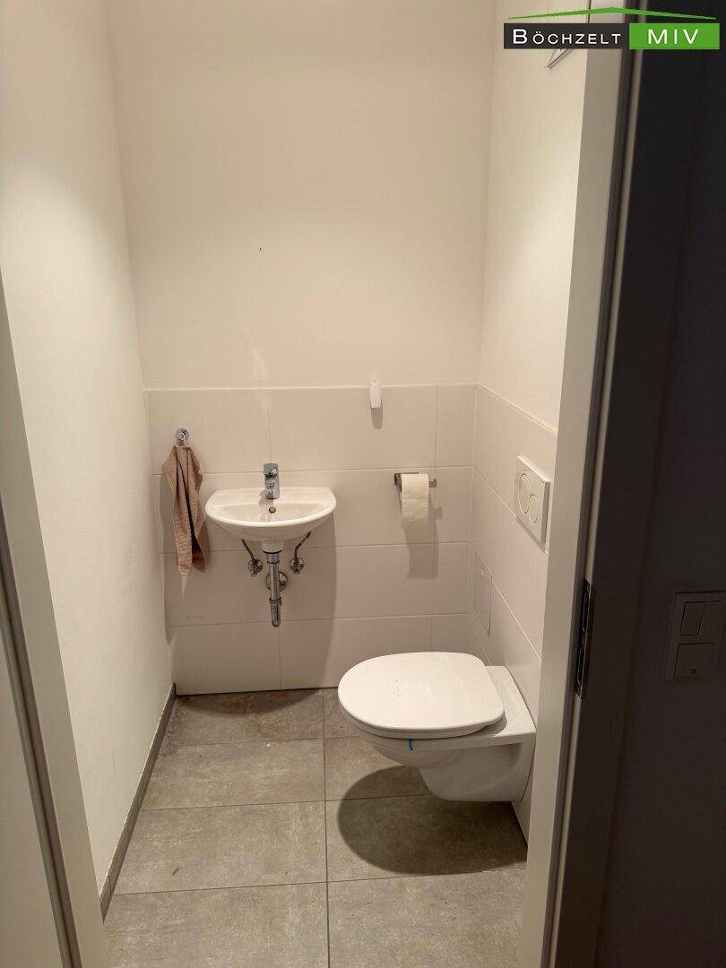 Separates WC mit wandhängender Toilette und kleinem Handwaschbecken, praktisch und funktional.