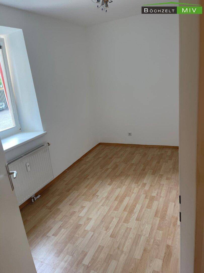 Helles Schlafzimmer mit Laminatboden und Fenster, bereit für individuelle Einrichtungsideen.