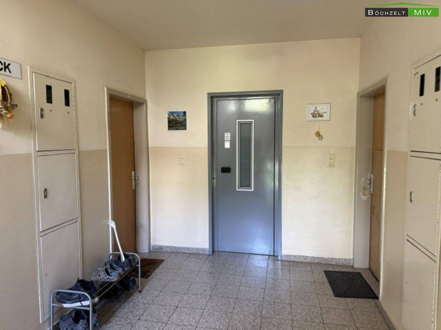 Eingangsbereich mit Fliesenboden, mehreren Türen und Schuhregal.