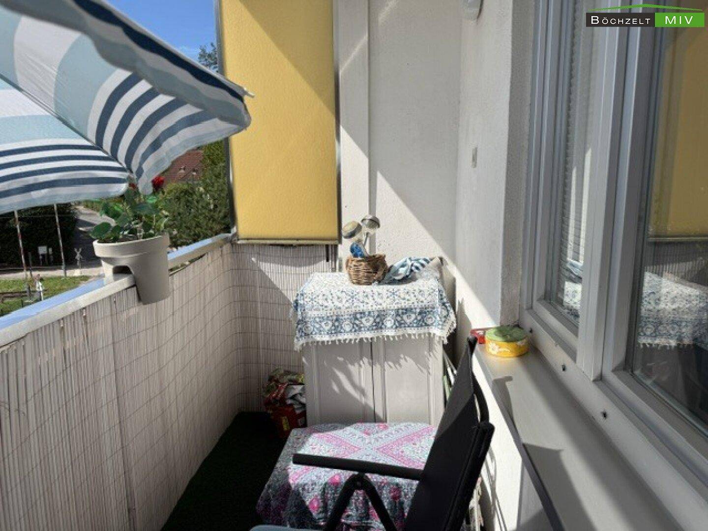 Kleiner, gemütlicher Balkon mit Sonnenschirm und Sitzgelegenheiten.