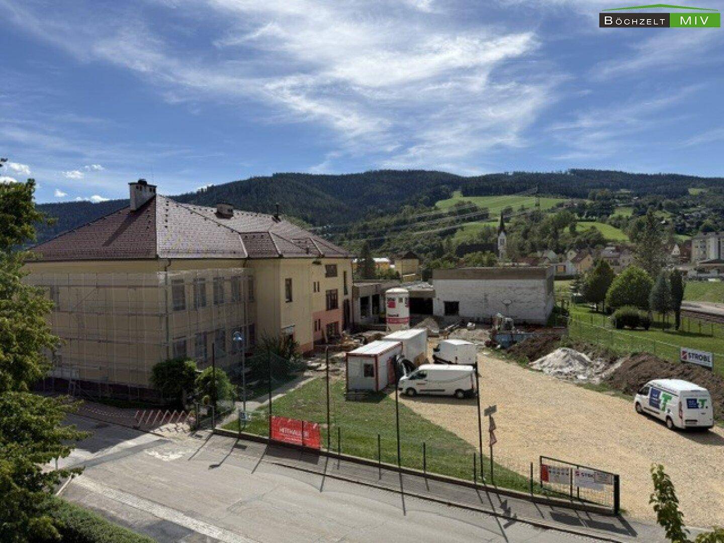 Panoramablick auf die umliegende Landschaft mit Bergen, Gebäuden und Baustellen.