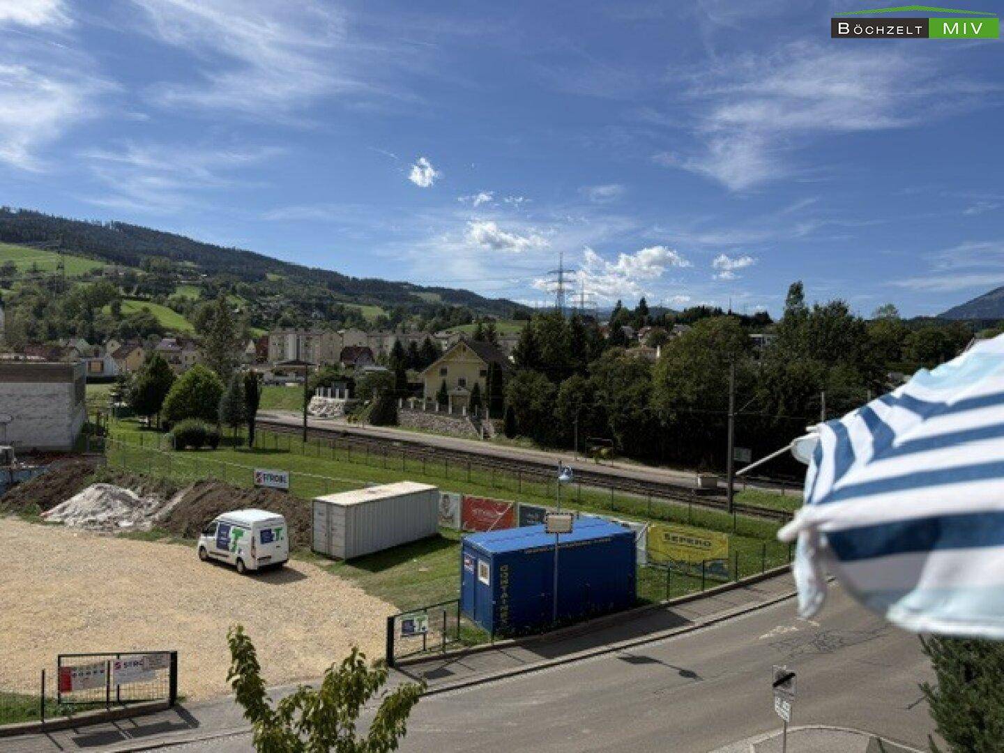 Weitblick über die Umgebung mit Bergen, Bahnlinie und Baustellenaktivitäten.